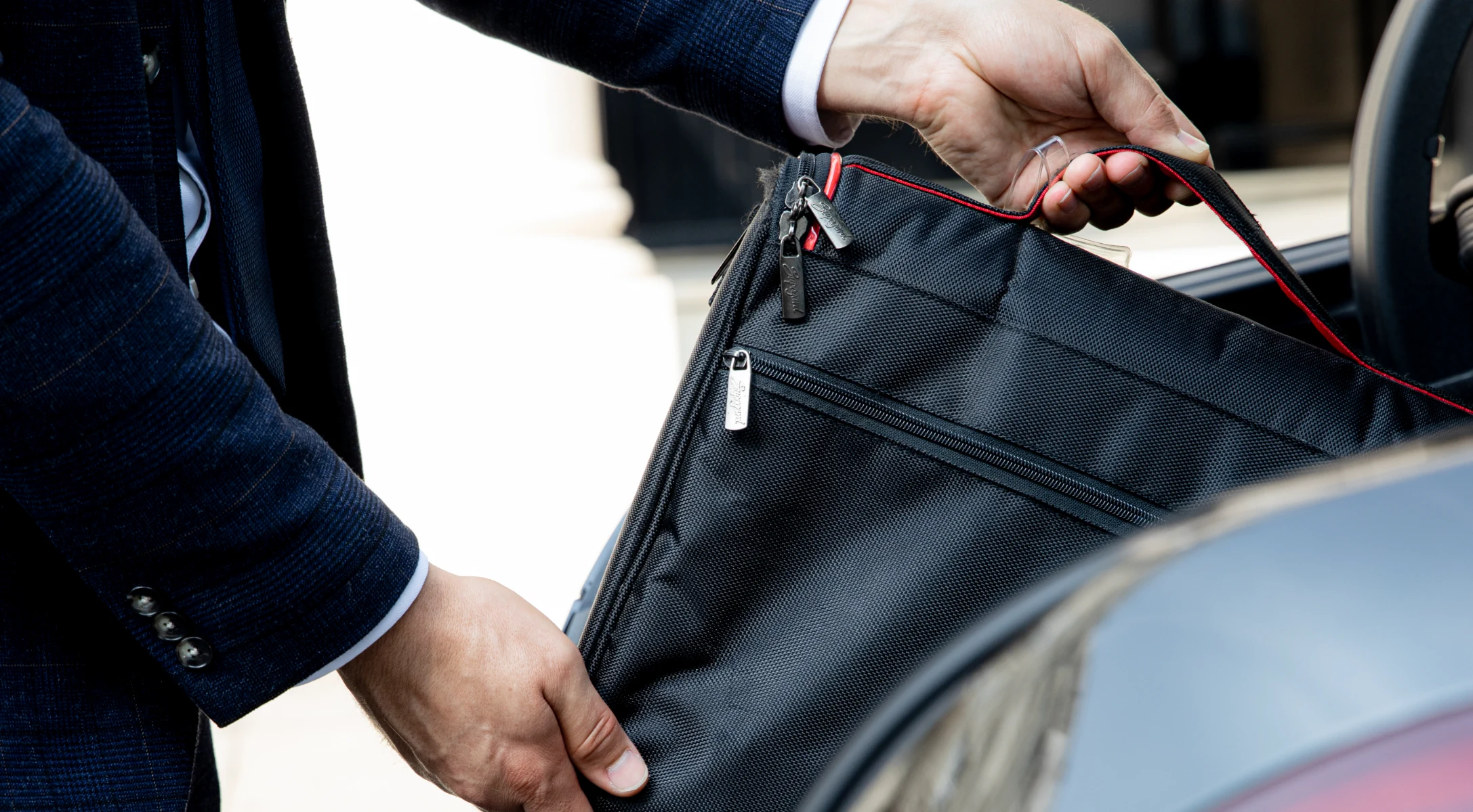 Chauffeur placing passengers bag in the trunk at the airport while providing luxury airport transfer in London.