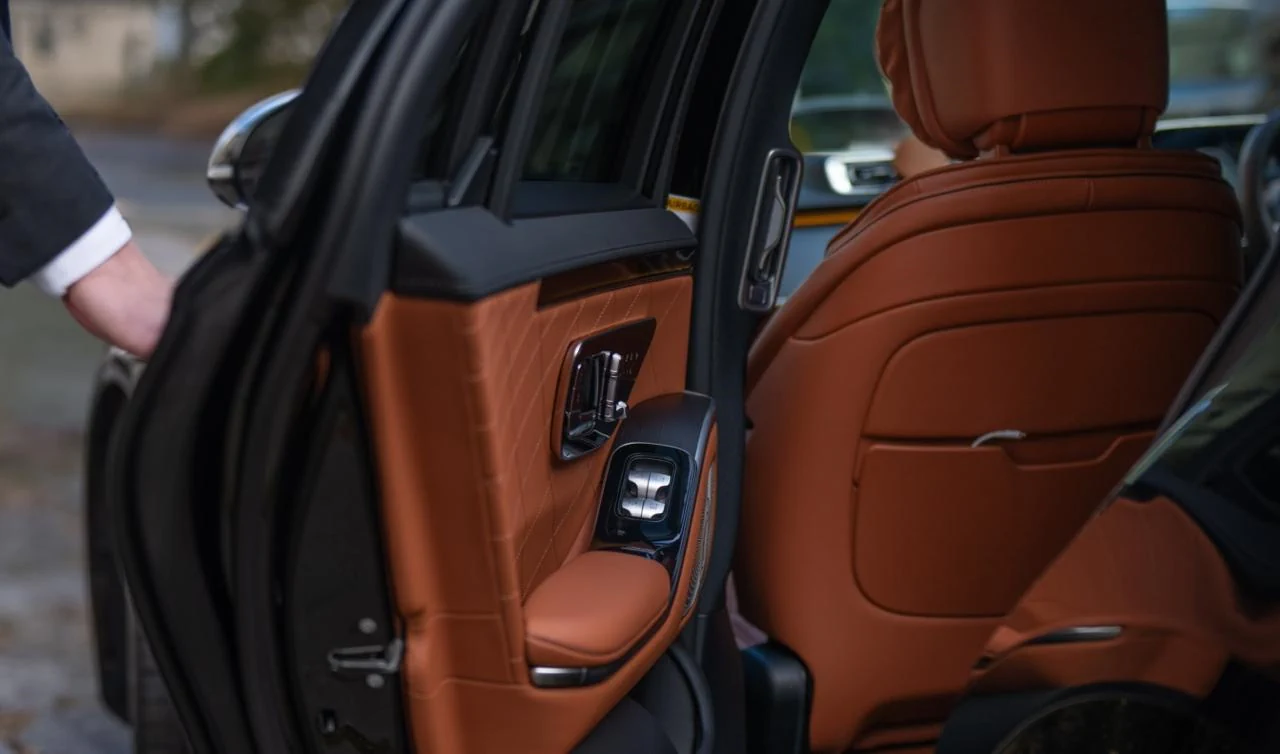 Man helping open car door for passenger.